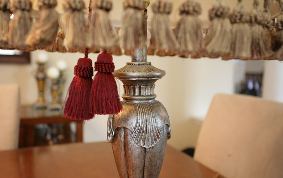 The base of the lamp with red and gold tassels hanging down.