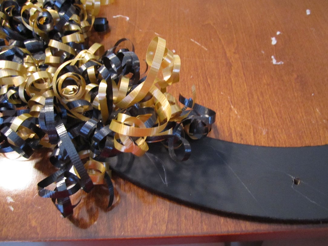 The curled black and gold ribbon on the wreath.