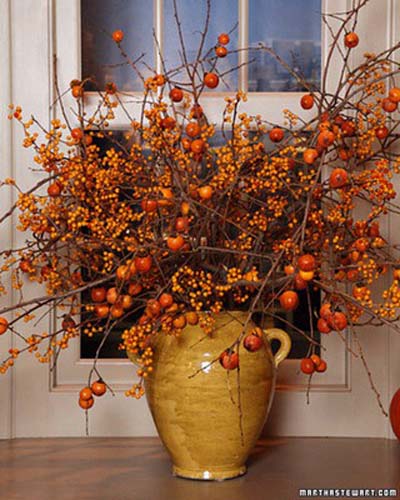 Gold vase filled with branches of orange and gold berries.