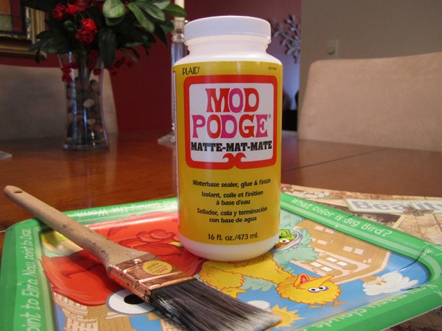 A bottle of mod podge and a brush beside it.