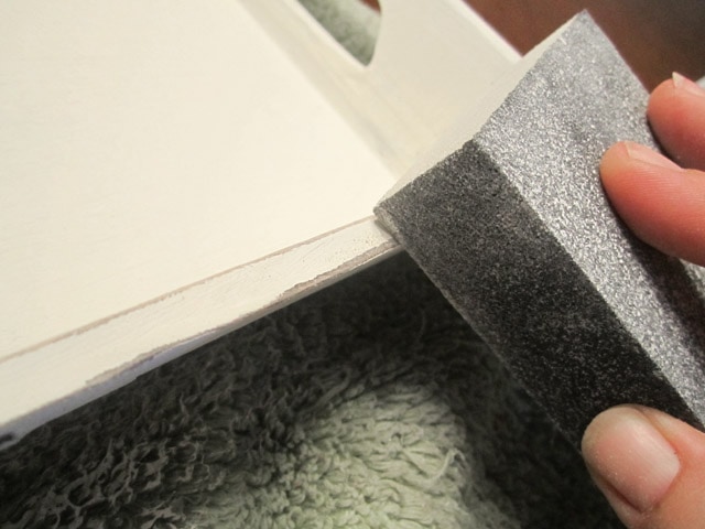 Using a sponge to paint the tray white.