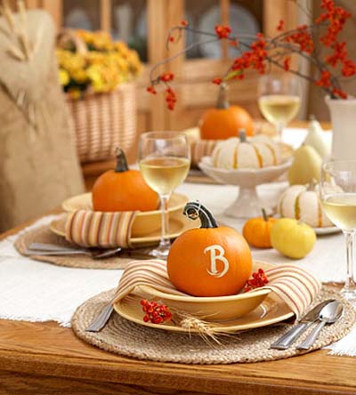 Pumpkin table place setting with a glass of white wine and red berry centerpiece.