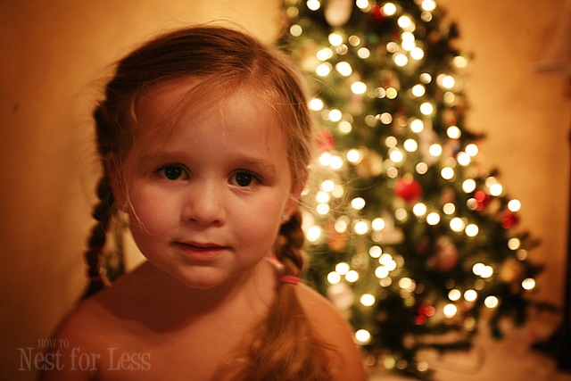 Little girl with braids and a tree behind her.