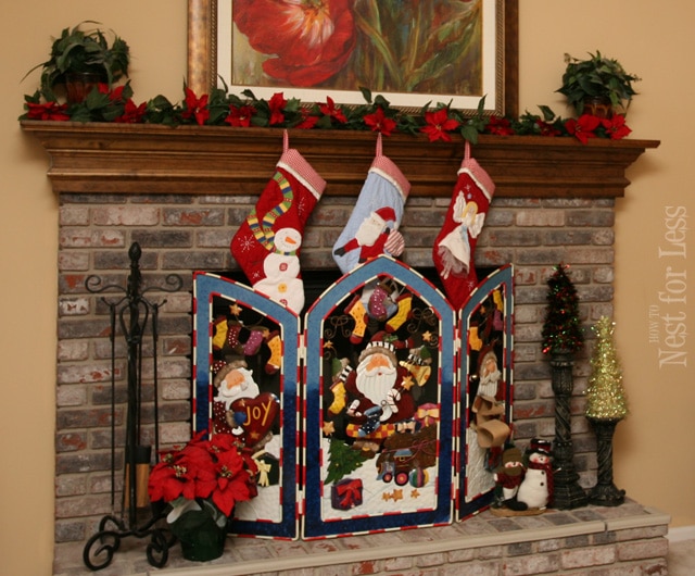 A decorative fireplace screen with stocking hanging above it.