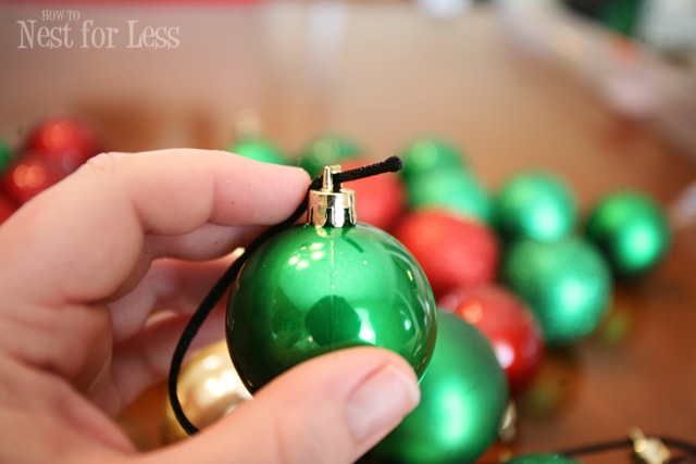 Putting black cording through a green ornament.