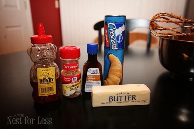 Butter, crescent rolls package, vanilla, honey and cinnamon on the counter.