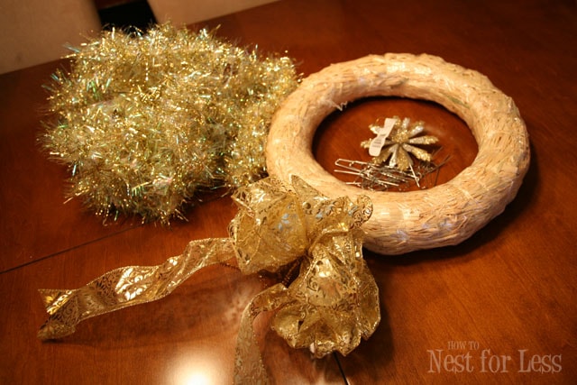 A wreath circle, gold tinsel and a gold bow on the floor.