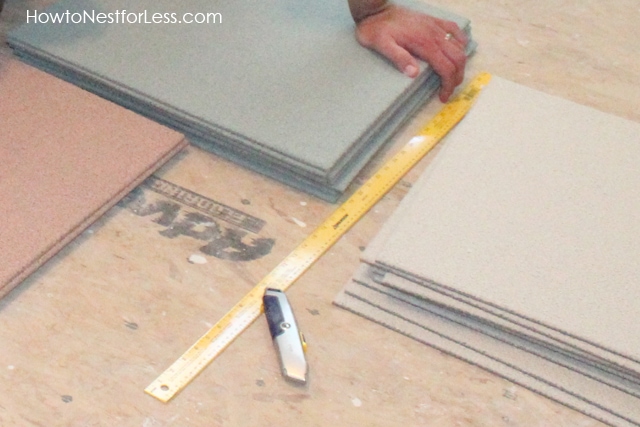 The tiles in a stack on the floor with facto knife and ruler.