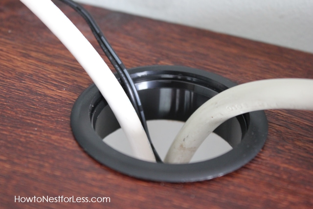 A hole in desk with cords going through it.