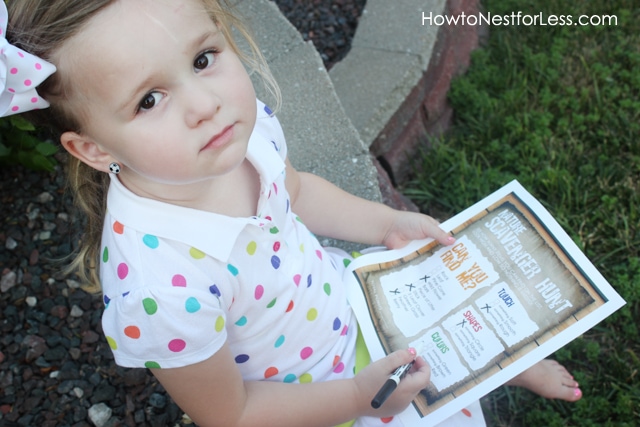 Little girl holding a nature scavenger hunt paper.