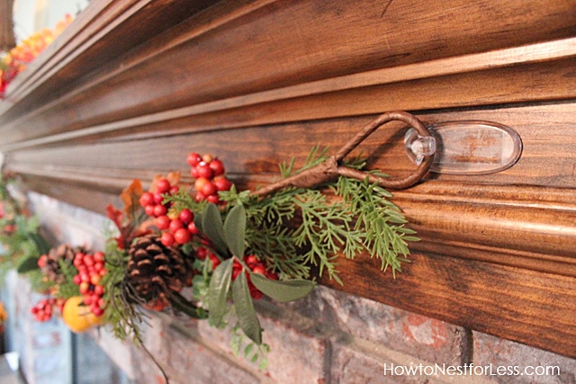 Clear hooks holding up the garland on the fireplace.