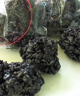 Black Christmas coal treats some in a plastic bag and some lying on the counter.