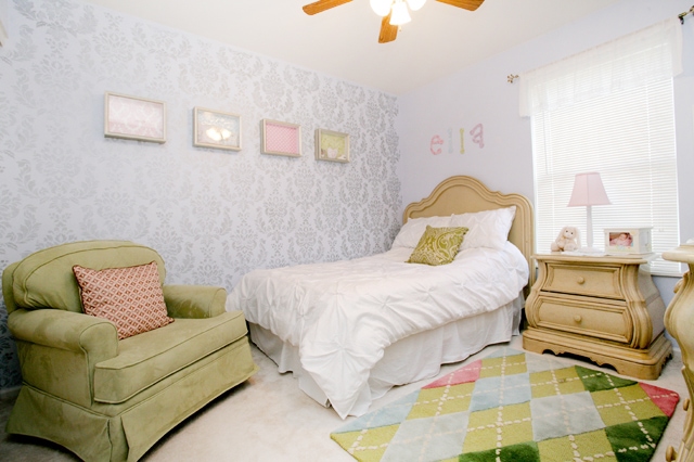 A little girls bedroom with wallpaper and pictures on the wall.