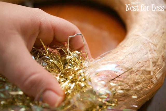 Using pins to put the tinsel on the wreath.