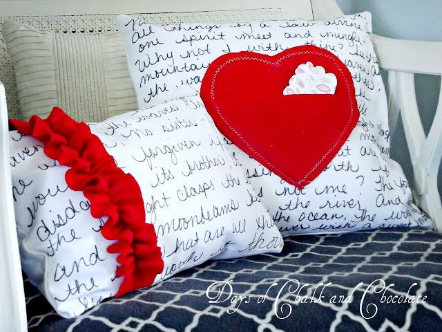 White pillows with black writing an a large red heart on it.