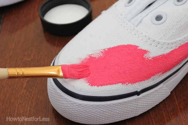 Brushing pink paint on the white shoe.