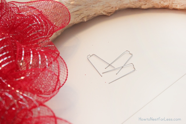 Pinning the red ribbon onto the wreath form.