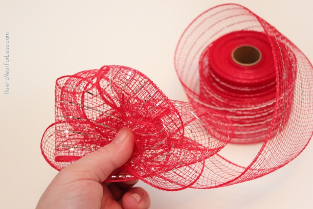 Holding the red mesh ribbon between two fingers.