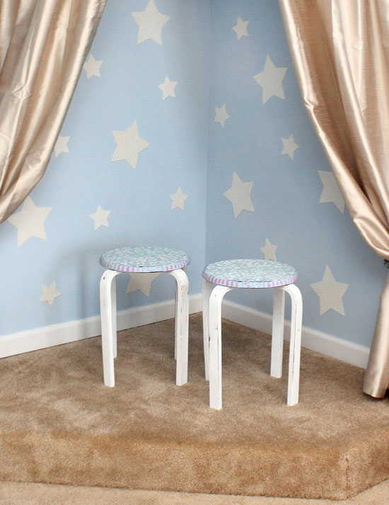 The distressed stenciled stools in front of a star wall and gold curtains.