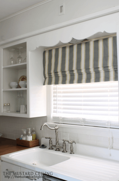 A window shade in striped light green and white in the kitchen.