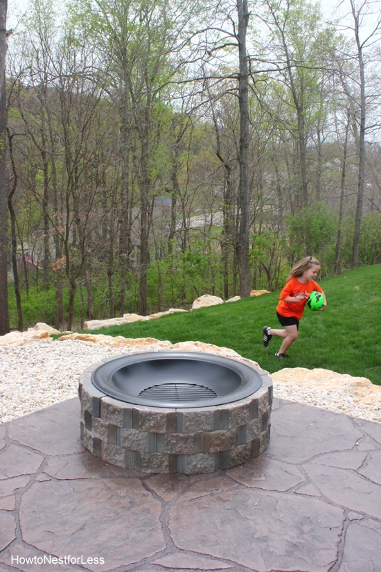 Little girl playing with a soccer ball, beside the fire pit.
