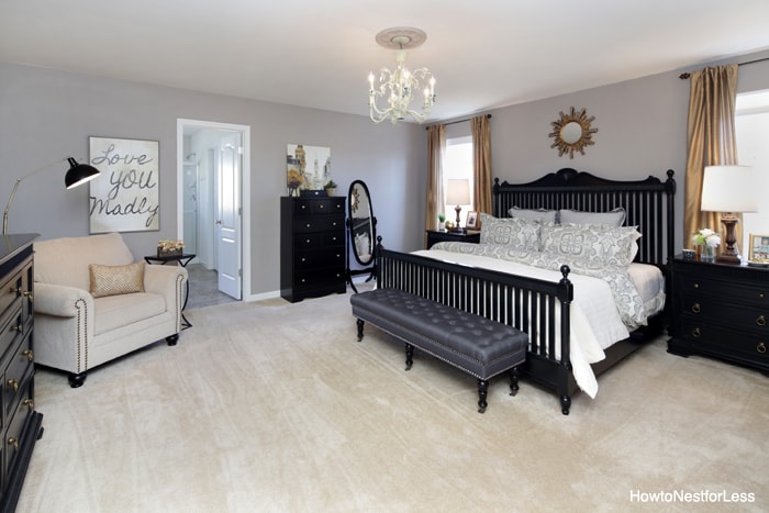 Large master bedroom with dark framed bed and armchair in corner.