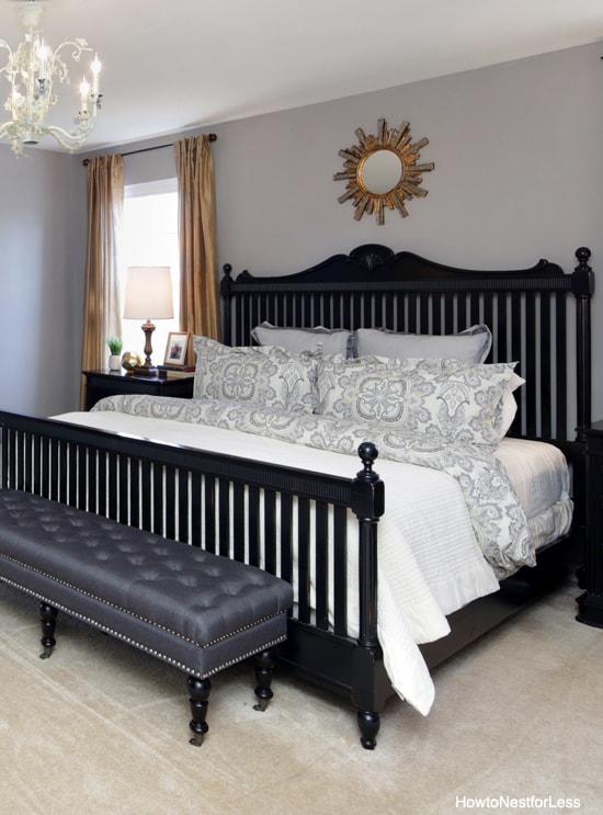 Black bed frame with white bedding and mirror over bed.