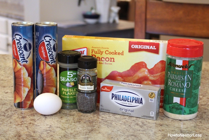Crescent roll packages, spices, cream cheese, parmesan, and egg and bacon on the kitchen counter.