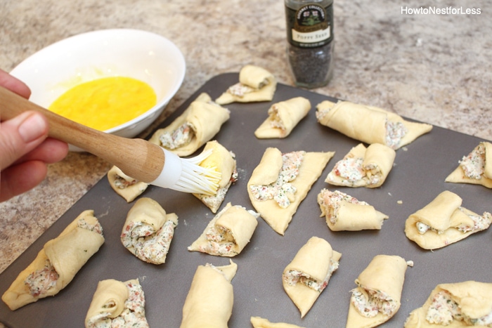 Brushing the rolled bacon cheese puffs with egg.