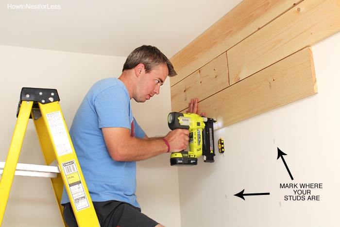 Man on a ladder marking the studs for the plank wall.