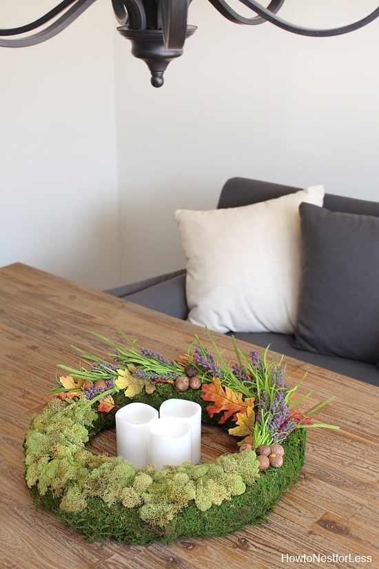 Candles inside the circle of the wreath with a grey couch in the background.