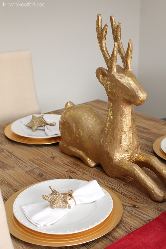 Up close picture of the gold deer beside the white and gold plates.