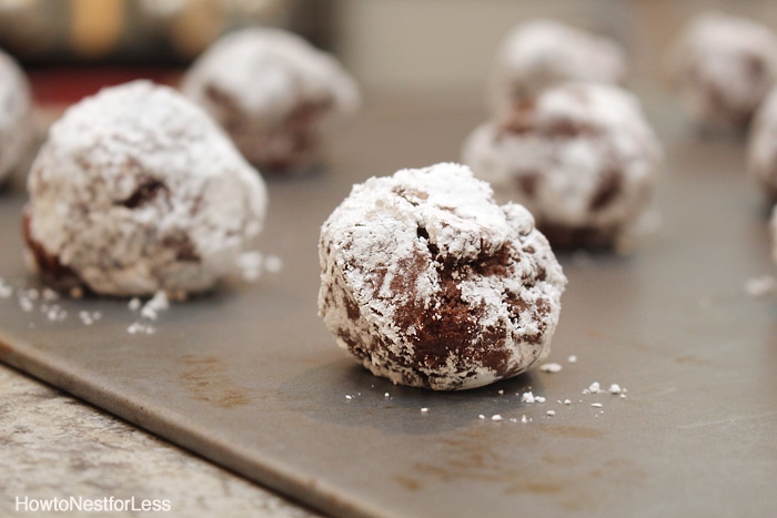 The batter rolled into balls and powdered sugar on a baking sheet.