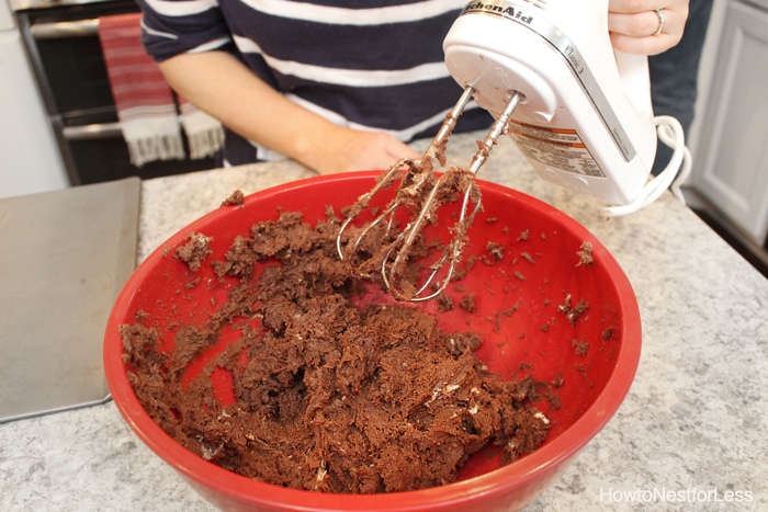 combining the ingredients in a red bowl with an electric hand held mixer.