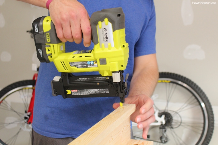 A man holding an electric nail gun on the wood.