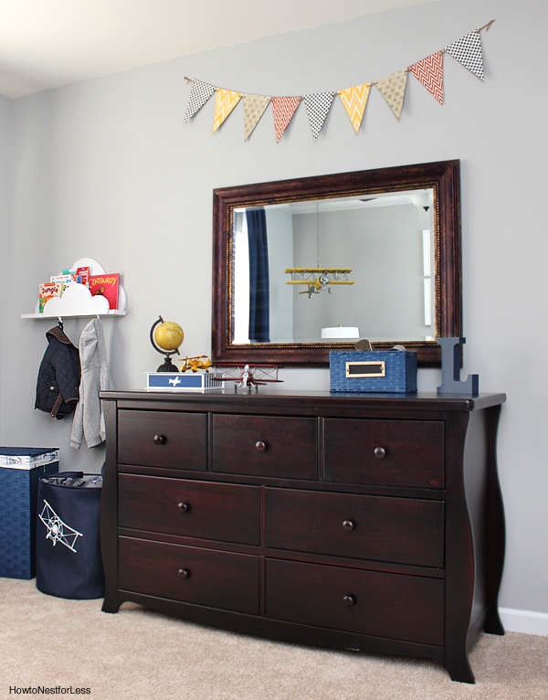 Jackets hanging off the cloud bookshelves with brown dresser in room.