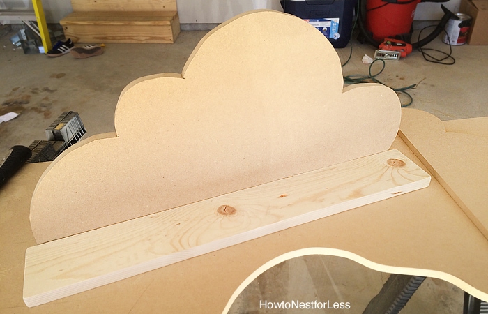 The cloud shape on floor with wooden piece in front of it.