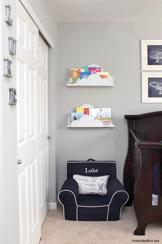 Painted white cloud bookshelves hanging on wall with child's chair underneath.