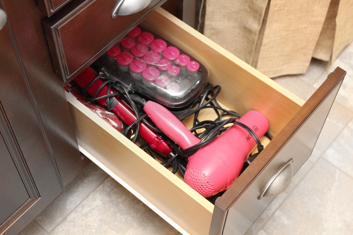Hair dryer, curling iron and curlers in bottom of the drawer.