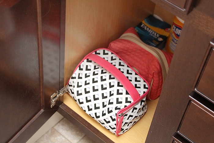 Makeup bags, cleaning supplies and feminine products in cabinet.