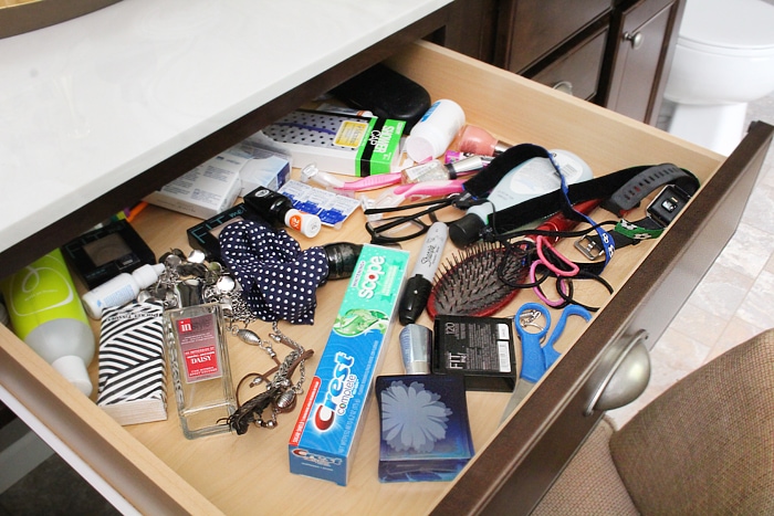 A messy drawer in the vanity that is opened.