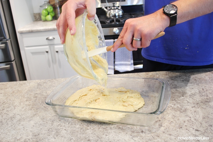 Cake batter being poured in a glass baking dish.