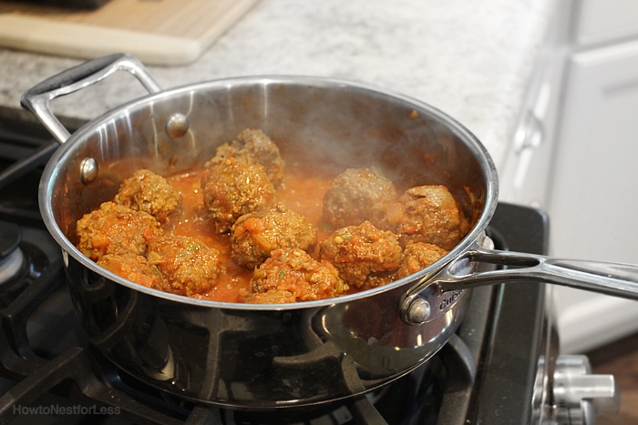A saucepan on the stove with the Mexican meatballs cooking inside it.