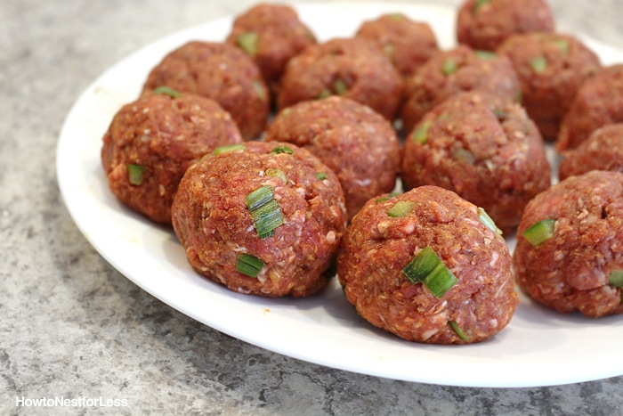 Raw meatballs on a white plate ready for cooking.