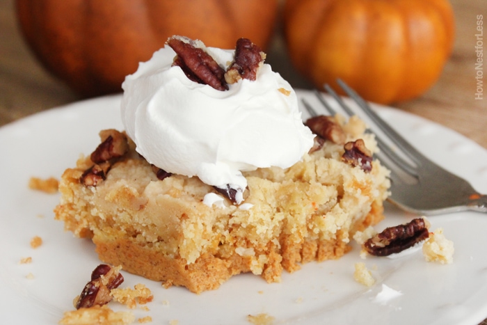 White plate with a slice of pumpkin pie cake on it and dollop of whip cream.