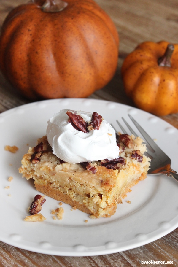 Pumpkin pie cake on a white plate with orange pumpkins beside it.