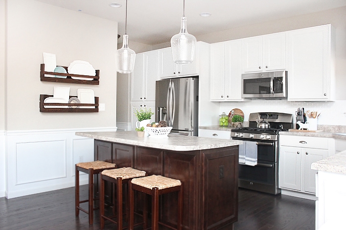 The white kitchen with stainless steel appliances and a wooden rack on the wall.