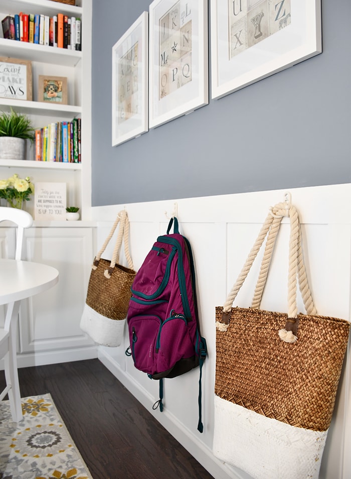 Hooks on the wall with a backpack and bags on the hooks.