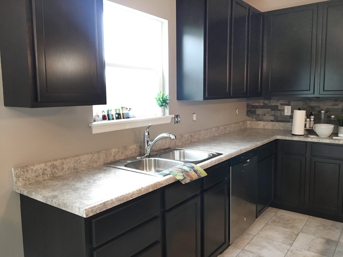 Dark wood cabinets and light counters in kitchen.