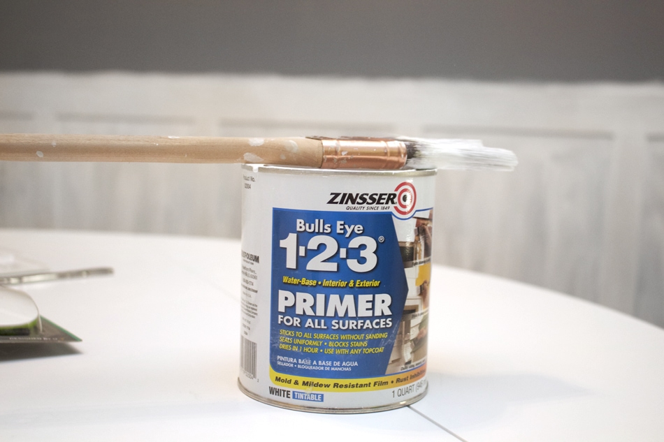 Primer can on the table with a paint brush on top of it.